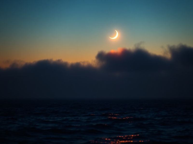 A wide-angle photograph of the Venus Moon conjunction over a city skyline at twilight, with Venus as a bright point near the