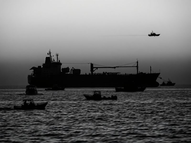 A moody, cinematic shot of an aging oil tanker sailing at dusk, its hull rusted and AIS transponder dark. The ship moves thro