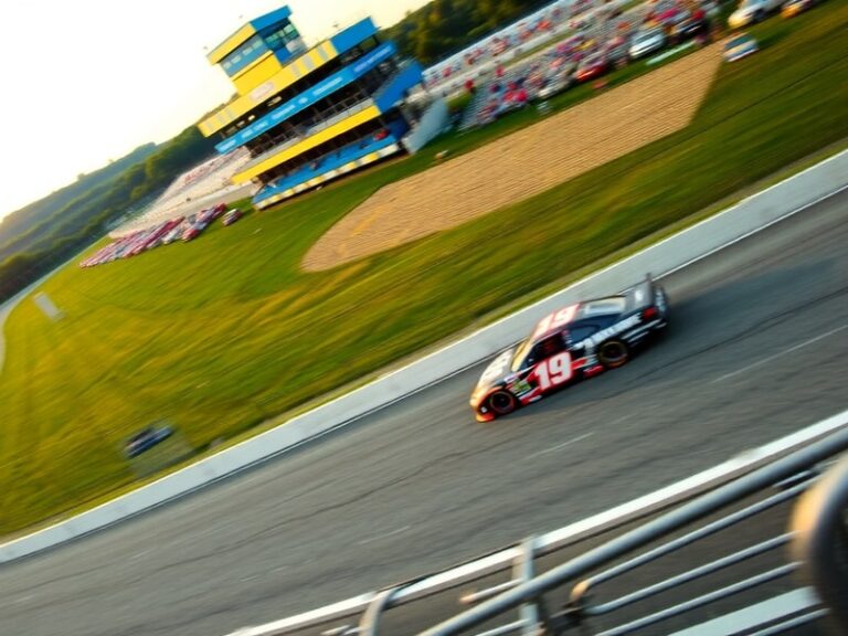 Aerial view of Pocono Raceway's 2.5-mile triangular track surrounded by the Pocono Mountains, with cars racing on the high-ba