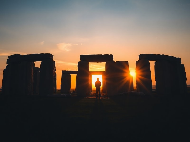 A vibrant scene of a summer solstice celebration at Stonehenge at sunrise, with crowds gathered around the ancient stones as