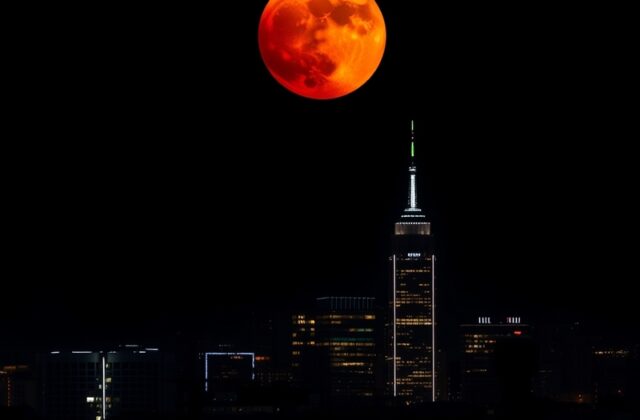 A high-resolution photograph of a Blood Moon total lunar eclipse, showing the deep red-orange color of the Moon fully immerse